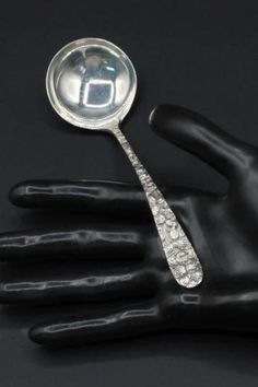 a silver spoon sitting on top of a black glove