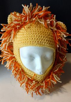 a crocheted hat with orange and white yarns on the top of it