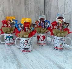 three coffee mugs filled with assorted candy and candies on top of a table