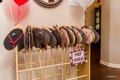 a bunch of hats are hanging on a rack with balloons and streamers in the background