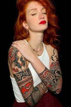 a woman with red hair and tattoos on her arms