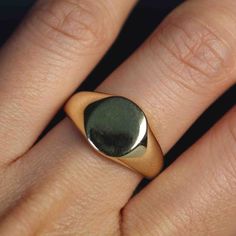 a woman's hand with a gold and black ring on top of her finger