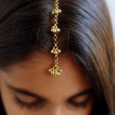 a close up of a woman wearing a gold chain with flowers on it's head