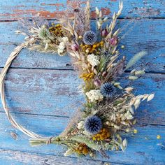 a wreath made out of dried flowers on a blue wooden background