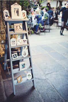 an old ladder with pictures on it sitting in the middle of a sidewalk next to people