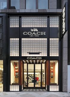 the entrance to a luxury store with glass doors and windows on both sides, in front of a tall building