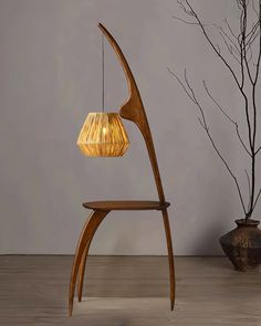 a wooden chair sitting next to a vase with a lamp on it's side