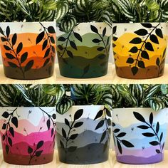 four potted plants with leaves painted on them in different colors and sizes, sitting next to each other