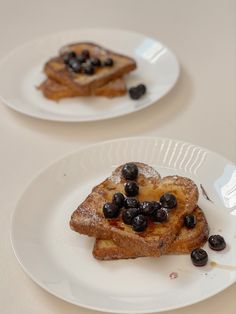 two white plates topped with french toast and blueberries