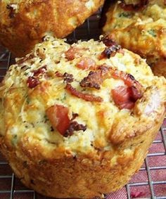 three muffins sitting on top of a wire rack with bacon and cheese in them