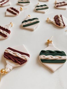 some very pretty earrings on a white table with other items in the shape of hearts