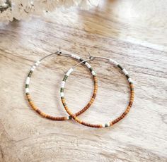 White, olive, mustard, and rust seed bead earrings, 1 ³/⁴ inches in diameter.  Nickel free hoops. Choose gold or silver hoops. Return to shop 👇 https://wyldsparrowjewelry.etsy.com PLEASE MAKE SURE YOUR ADDRESS IS ENTERED CORRECTLY. IF YOU ARE DOING A GUEST CHECKOUT PLEASE PLEASE DOUBLE CHECK YOUR ADDRESS AND YOUR EMAIL. THANK YOU! *All feathers are cruelty free.  All hooks are lead and nickel free. All leather is genuine leather. *Please feel free to contact me with ANY questions or custom crea Bohemian Heishi Beads Small Hoop Earrings, Bohemian Small Hoop Heishi Bead Earrings, Bohemian Heishi Beads Hoop Earrings, Bohemian Hoop Earrings With Heishi Beads, Bohemian Hoop Beaded Earrings With Heishi Beads, Bohemian Heishi Beaded Hoop Earrings, Bohemian Hoop Earrings With Tiny Beads, Handmade Bohemian Hoop Beaded Bracelets, Bohemian Heishi Beaded Earrings With Ear Wire