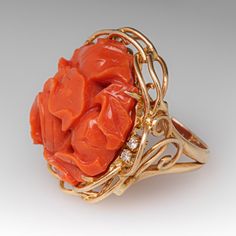 This fantastic vintage ring is centered with a carved floral design coral that is set into four-prongs. The coral is bordered with four (4) prong set round brilliant cut diamonds. The ring measures 25.9mm at the top, rises 12.7mm above the finger, tapering to 2.5mm wide and 0.8mm thick at the base of the shank. It is currently a size 4.5. Coral Elegant Wedding Rings, Elegant Coral Wedding Rings, Elegant Coral Ring Jewelry, Elegant Coral Rings For Anniversary, Elegant Carved Orange Jewelry, Elegant Orange Carved Jewelry, Brand Presentation, Coral Ring, The Coral