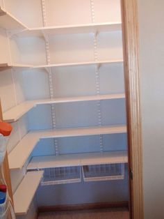 an empty pantry with white shelves and blue bins