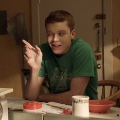 a young man sitting at a table in front of a microwave