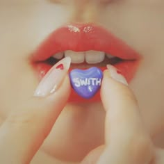 a woman holding a candy heart with the word south on it in front of her mouth