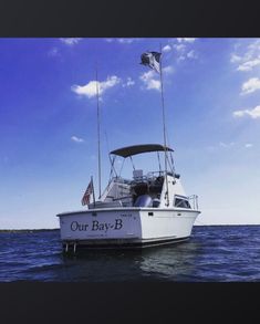 a white boat floating on top of the ocean next to a flag flying in the wind