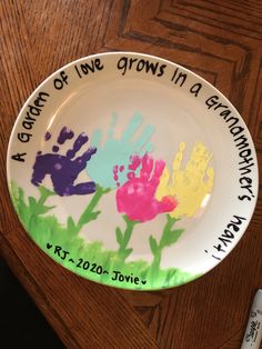 a plate with handprints on it that says, a garden of love grows in a grandmother's heart