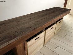 a large wooden table with two drawers on the bottom and one at the top, in front of a white wall