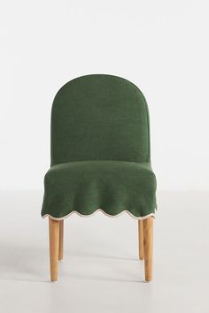 a green chair with scalloped back and wooden legs