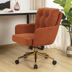 an orange office chair sitting on top of a hard wood floor next to a plant