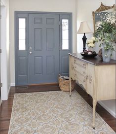 a blue front door in a house with a rug on the floor and a lamp