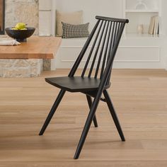 a black chair sitting on top of a wooden floor next to a bowl of fruit