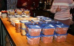 people are standing at a counter with food in plastic containers and cups on the table