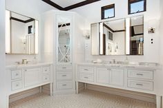 a large bathroom with two sinks and three mirrors on the wall, along with white cabinetry