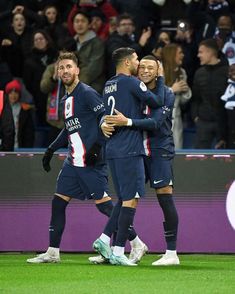 three soccer players congratulate each other on the field in front of a crowd