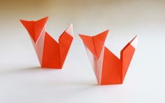 three orange origami birds sitting on top of a white table next to each other