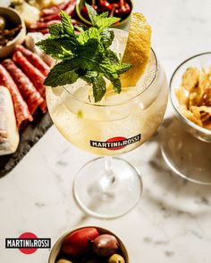 a glass filled with liquid sitting on top of a table next to bowls of food