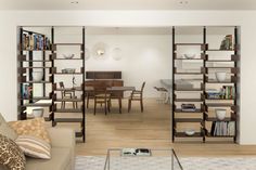 a living room filled with furniture and bookshelves next to a dining room table