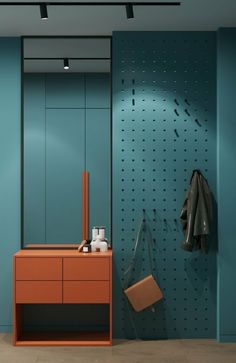 an orange dresser and mirror in a blue room with pegs on the wall behind it