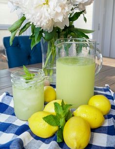 some lemons and limeade are sitting on a table with flowers in the background