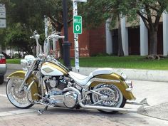 a gold and white motorcycle parked on the side of the road next to a street sign