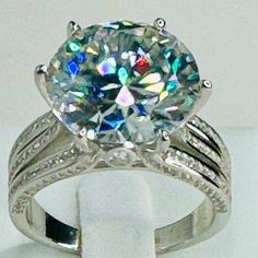 a white gold ring with an oval cut diamond surrounded by multicolored stones and diamonds