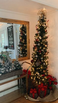 a decorated christmas tree in the corner of a room next to a mirror with lights on it