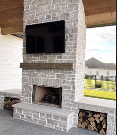 a tv mounted on the side of a brick fireplace in a home's outdoor living area