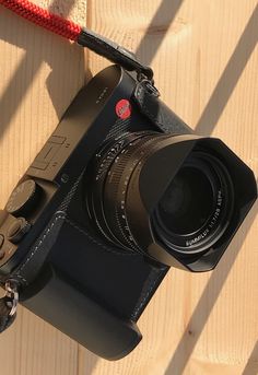 a camera with a lens attached to it on a wooden table next to a red rope