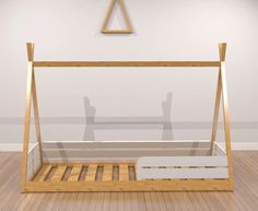 a wooden bed frame sitting on top of a hard wood floor next to a white wall