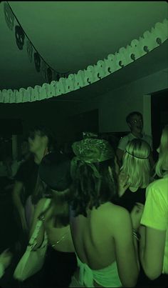 a group of people standing around each other in a room with paper decorations on the ceiling