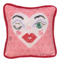 a pink pillow with a heart shaped face on the front and eyes painted on it