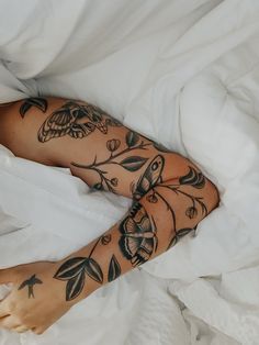 a person laying in bed with tattoos on their arms and legs, covered by white sheets