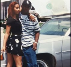 a man standing next to a woman in front of a car