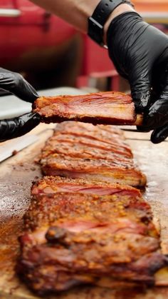 a person in black gloves is slicing meat on a cutting board