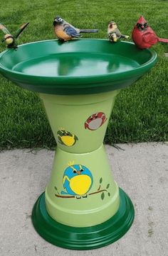 three birds sitting on top of a green bird bath