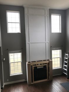 an empty living room with two windows and a fire place in the middle of it