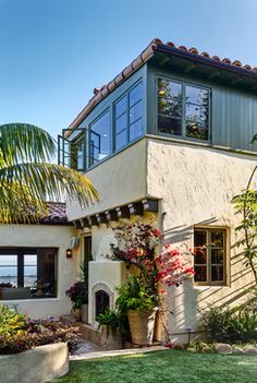 a house with lots of plants in front of it and a view of the ocean