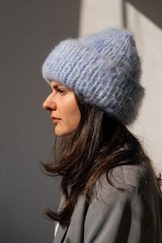 a woman with long hair wearing a blue knitted hat on her head and looking off into the distance